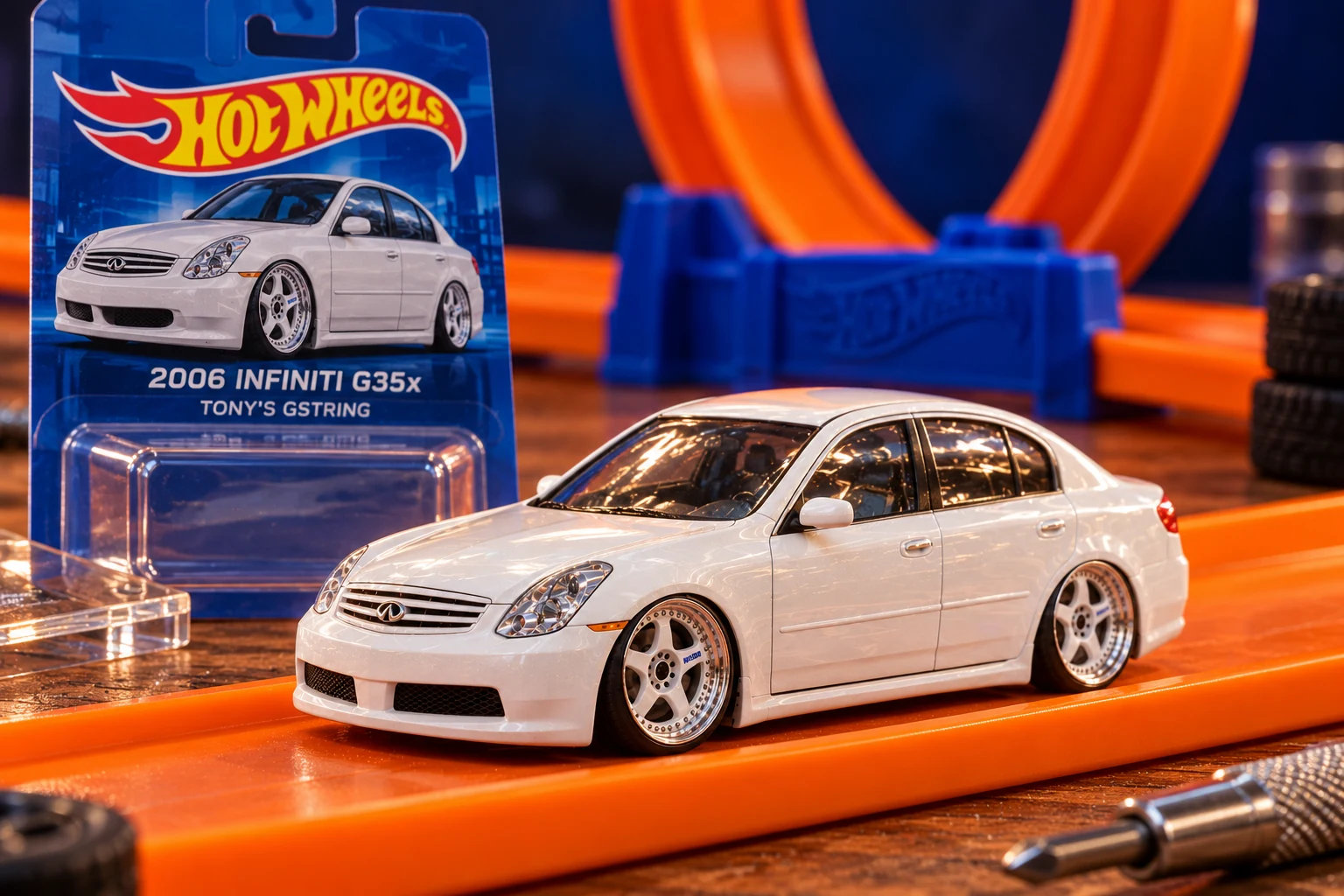 A fictional toy-car concept of Tony’s white 2006 Infiniti G35x, displayed on orange track beside miniature-car packaging.