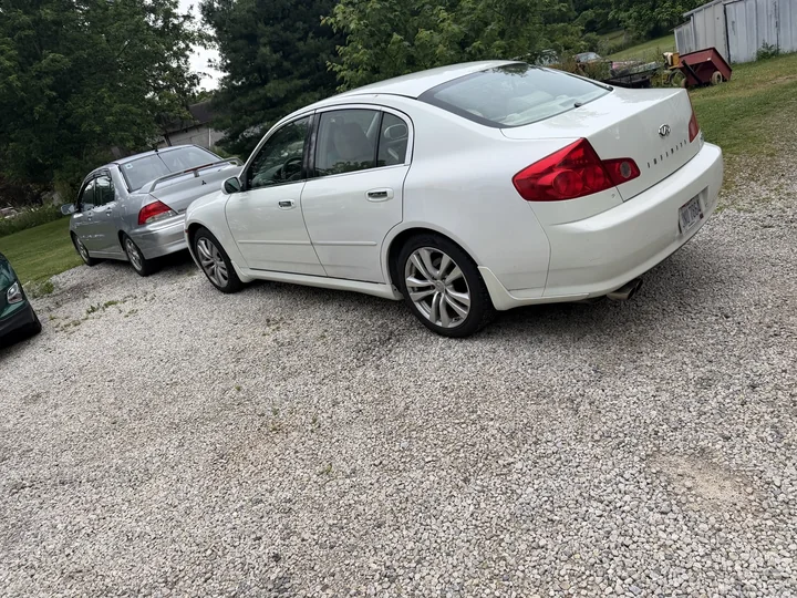 Actual rear three-quarter view of Tony parked on gravel beside other cars.