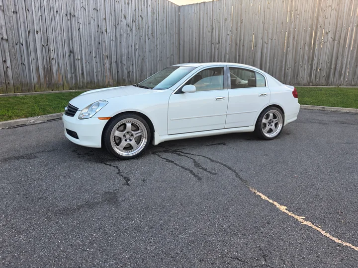 Tony’s white sedan with edited polished five-spoke WORK wheels, parked beside a wooden fence.
